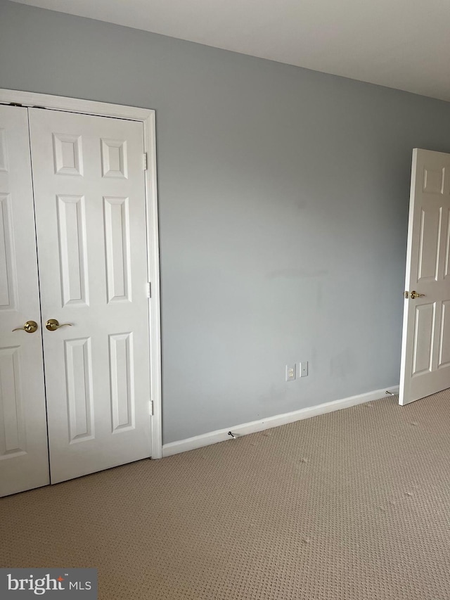 unfurnished bedroom with light colored carpet and a closet