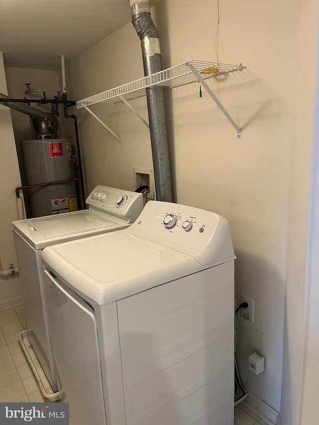 washroom featuring gas water heater, washer and dryer, and light tile patterned floors