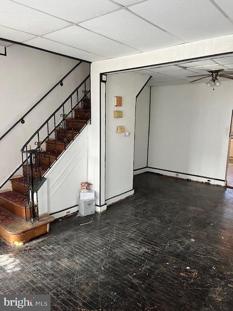 basement with a paneled ceiling and ceiling fan