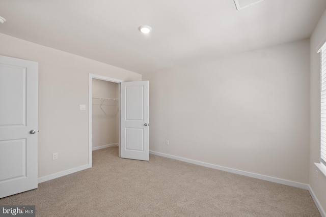 unfurnished bedroom featuring a walk in closet, light carpet, and a closet