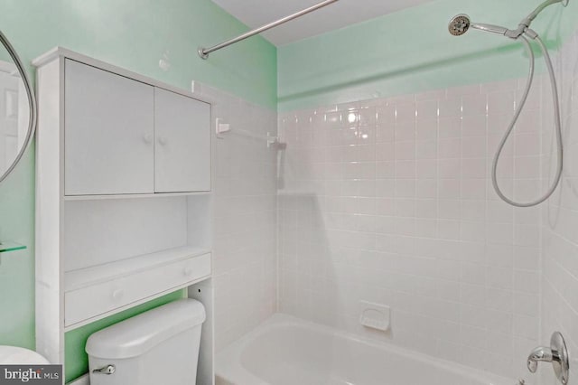 bathroom with tiled shower / bath combo and toilet