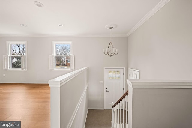 stairs with crown molding, hardwood / wood-style floors, and a notable chandelier