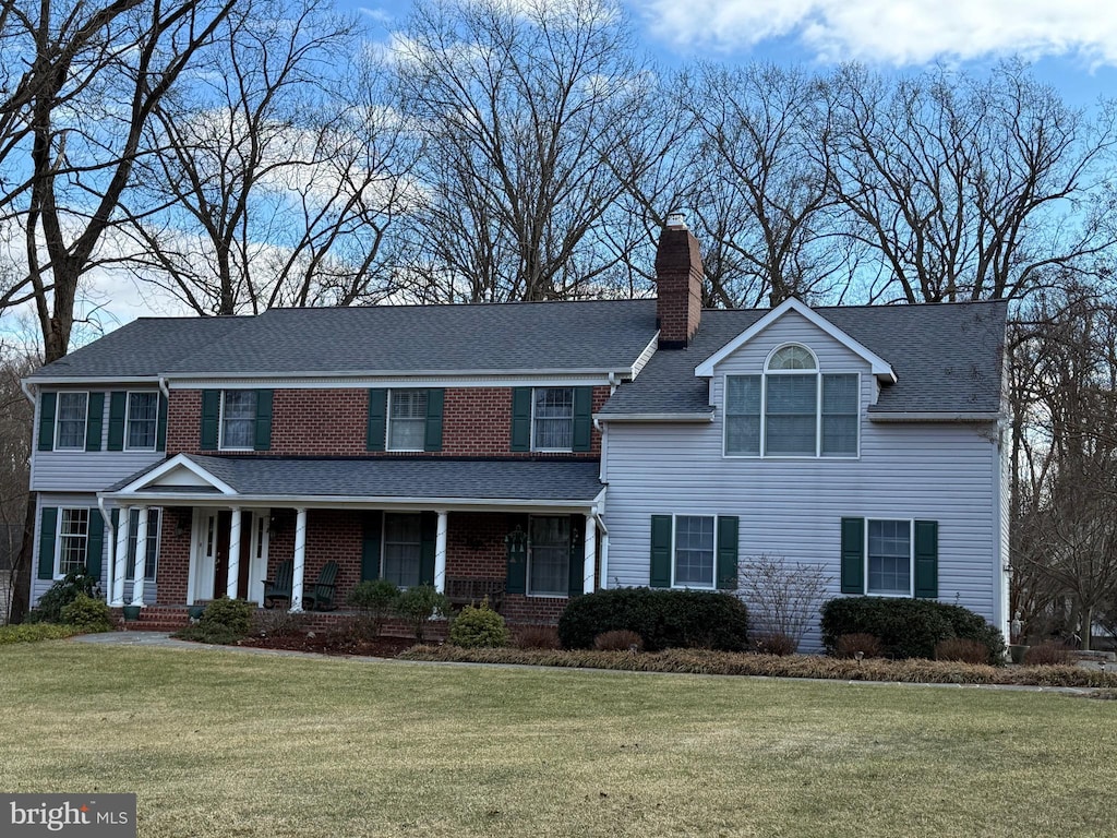 colonial home featuring a porch and a front lawn