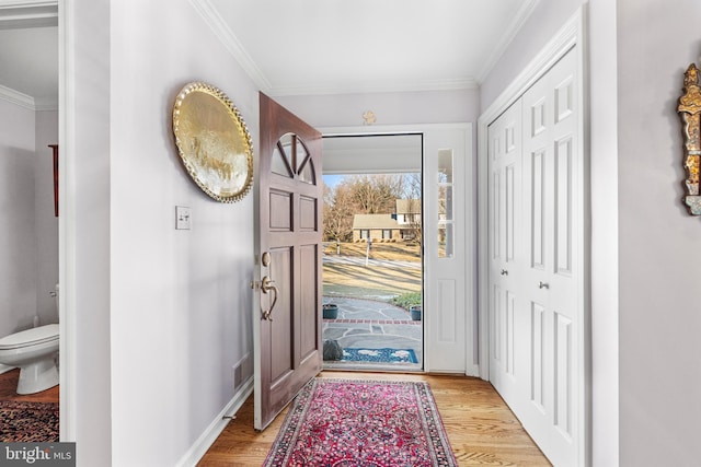 foyer with baseboards, crown molding, and light wood finished floors