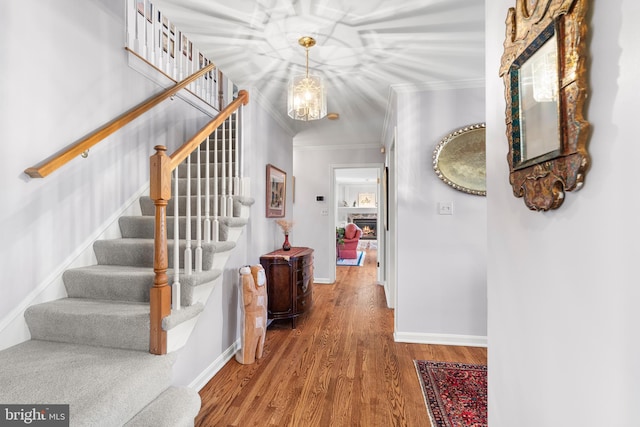 interior space with baseboards, wood finished floors, stairs, crown molding, and a notable chandelier