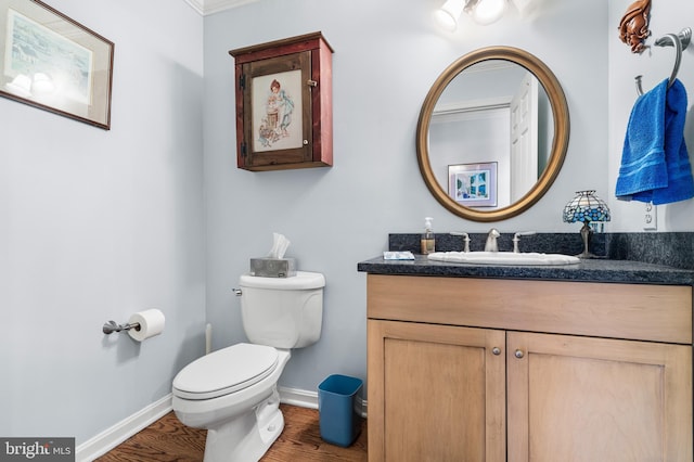 half bathroom featuring toilet, baseboards, wood finished floors, and vanity