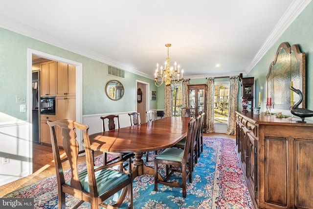 dining room featuring a chandelier, light wood finished floors, visible vents, and ornamental molding