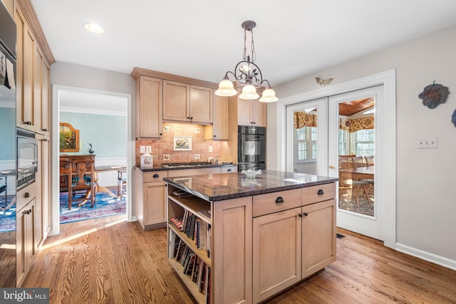 kitchen featuring light wood-style flooring, black appliances, a center island, light brown cabinetry, and pendant lighting