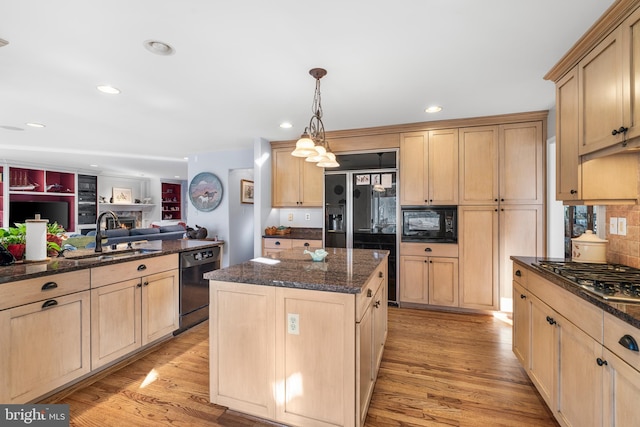 kitchen with open floor plan, a center island, light brown cabinetry, black appliances, and a sink