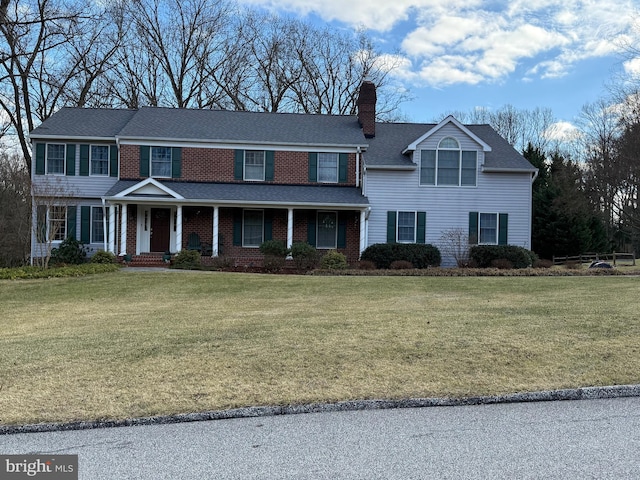 traditional-style home with a chimney, a front lawn, and brick siding