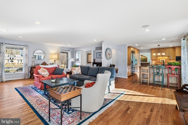 living room featuring light wood-style floors, visible vents, baseboards, and recessed lighting