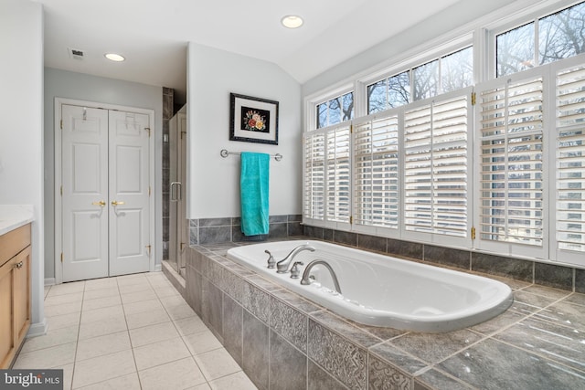 bathroom with a garden tub, a closet, vaulted ceiling, vanity, and tile patterned floors