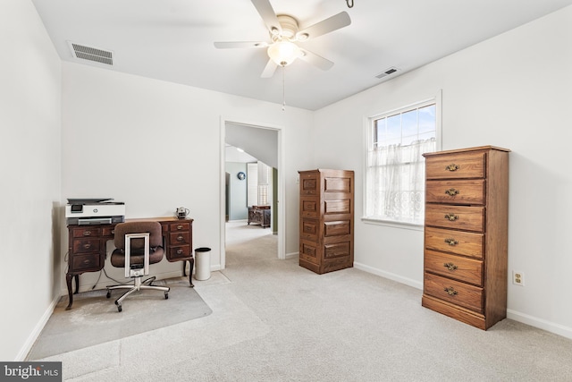 office space with a ceiling fan, light colored carpet, visible vents, and baseboards