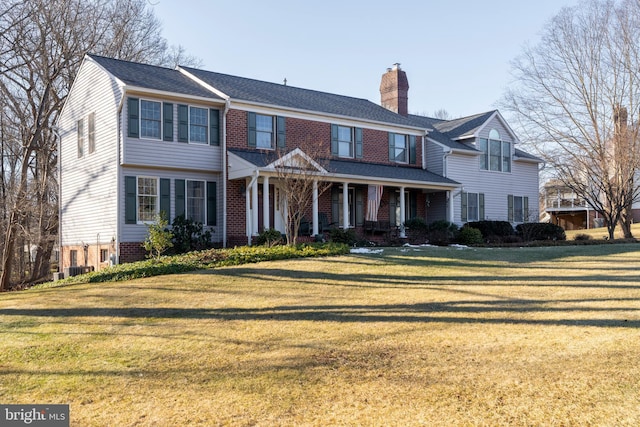 view of front of house featuring a front yard, brick siding, and a chimney