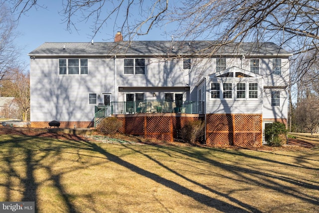 rear view of house with a wooden deck, a chimney, and a yard