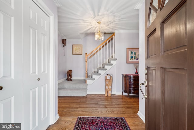 foyer entrance featuring baseboards, ornamental molding, stairway, and light wood-style floors