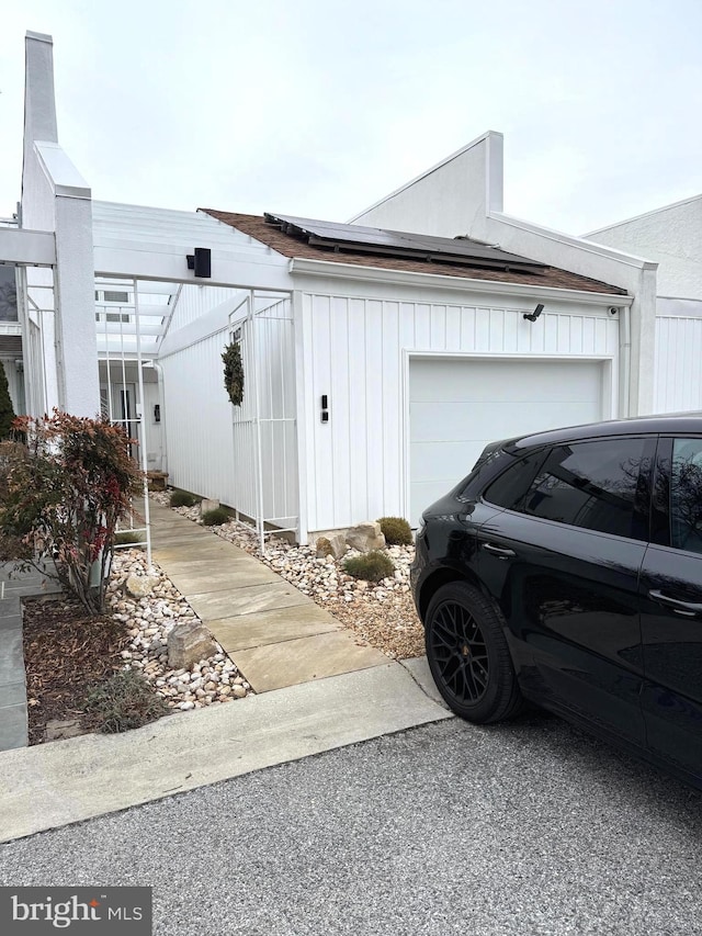 view of side of property featuring a garage and solar panels