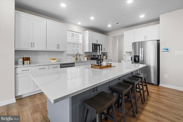 kitchen with sink, stainless steel appliances, white cabinets, and a kitchen island