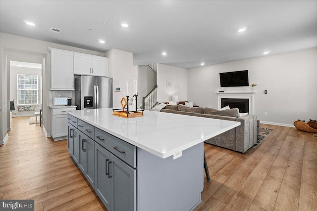 kitchen with a breakfast bar, stainless steel fridge, a center island, and white cabinets