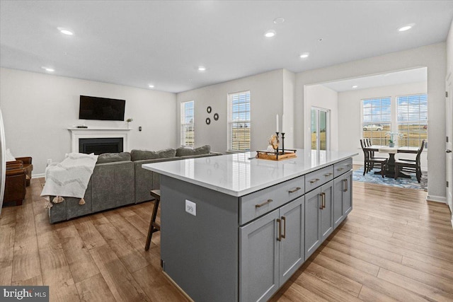 kitchen with a center island, gray cabinetry, light wood-type flooring, and a breakfast bar