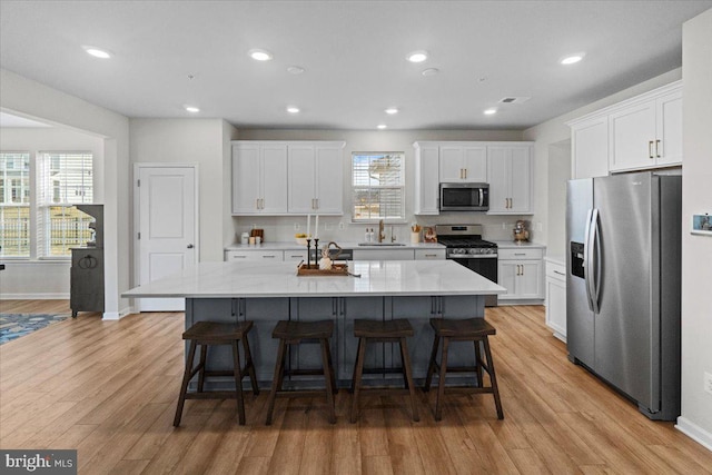 kitchen featuring a kitchen island, appliances with stainless steel finishes, sink, and white cabinets