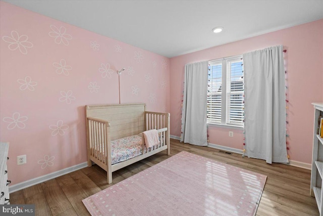 unfurnished bedroom featuring a crib and wood-type flooring