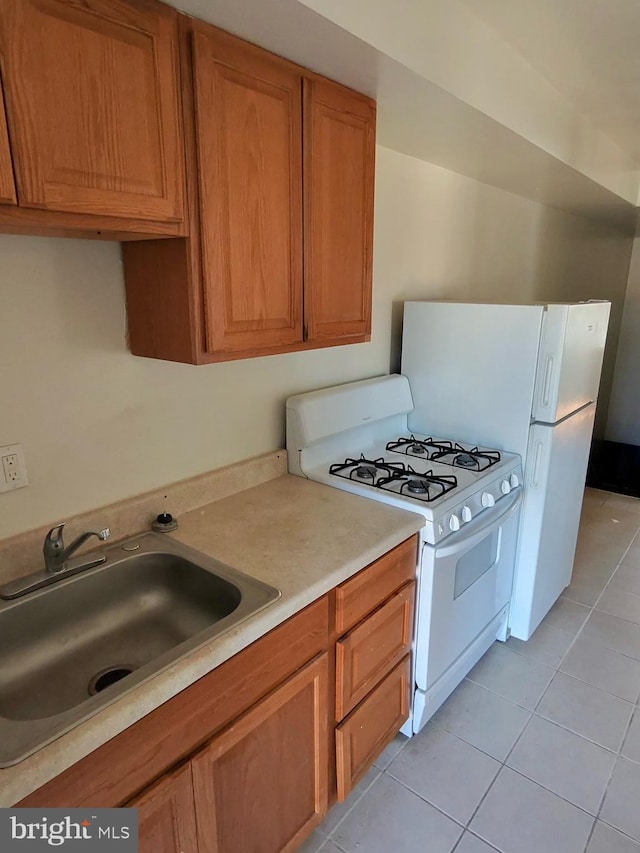 kitchen featuring light tile patterned flooring, white range with gas cooktop, and sink