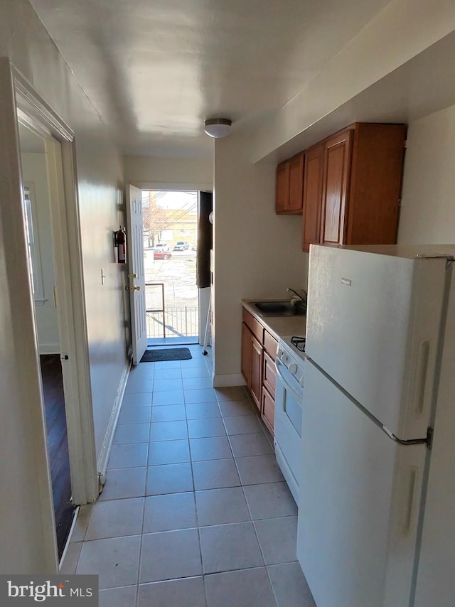 kitchen with light tile patterned flooring, white appliances, and sink