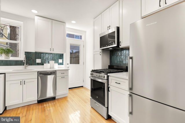 kitchen featuring light countertops, appliances with stainless steel finishes, a sink, and white cabinets