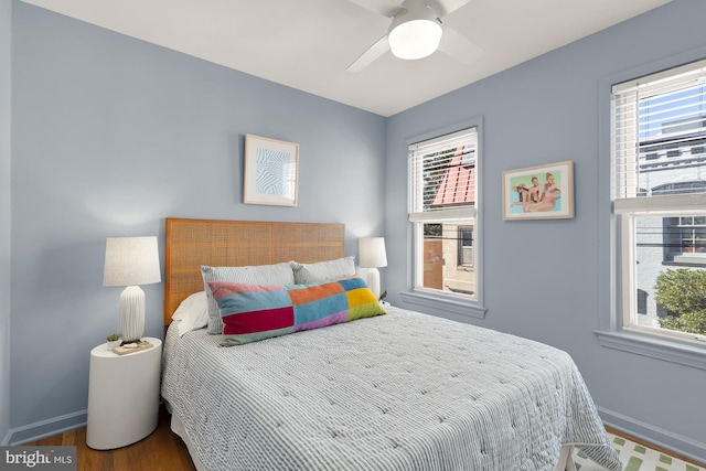 bedroom with ceiling fan, wood finished floors, and baseboards