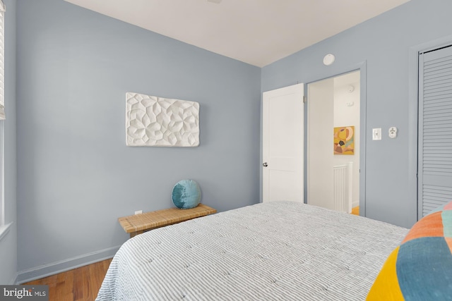 bedroom featuring a closet, baseboards, and wood finished floors