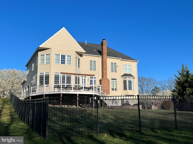 back of house featuring a yard, a chimney, a fenced backyard, and a wooden deck