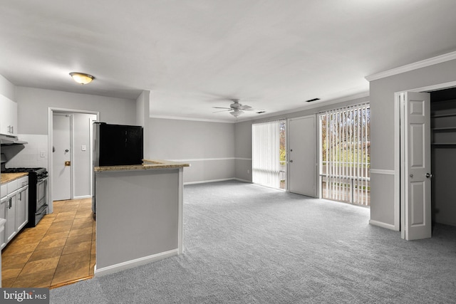 574 Wilson Bridge Dr Unit D-2, Oxon Hill, MD 20745 - kitchen with black range with gas cooktop, light carpet, fridge, ceiling fan, and white cabinets