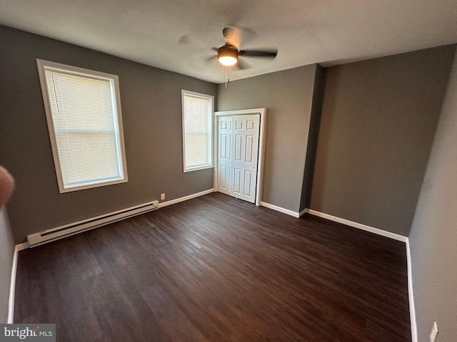 unfurnished bedroom with a baseboard heating unit, dark wood-type flooring, ceiling fan, and a closet