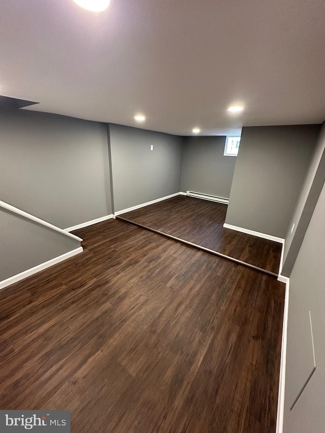 basement featuring a baseboard radiator and dark wood-type flooring