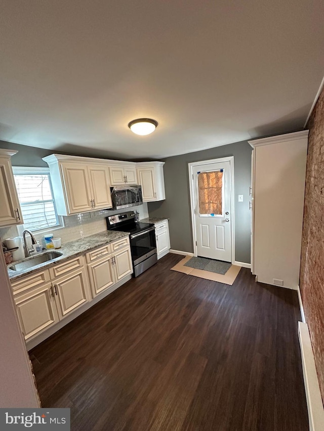 kitchen featuring sink, dark wood-type flooring, appliances with stainless steel finishes, tasteful backsplash, and light stone countertops