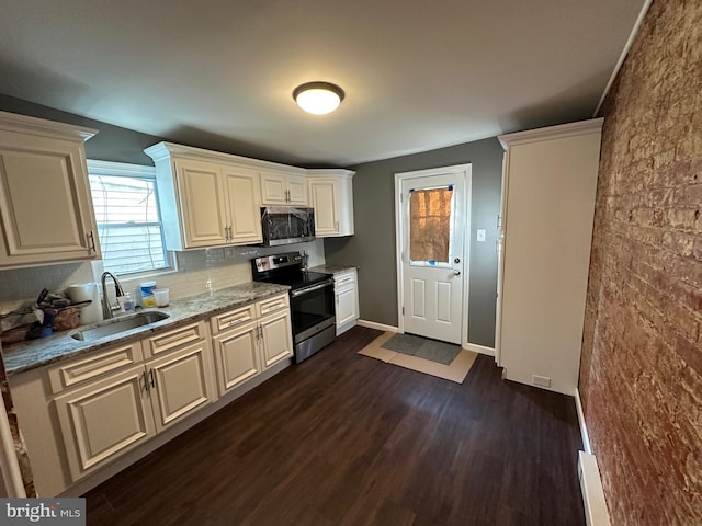 kitchen featuring appliances with stainless steel finishes, sink, decorative backsplash, light stone counters, and dark wood-type flooring