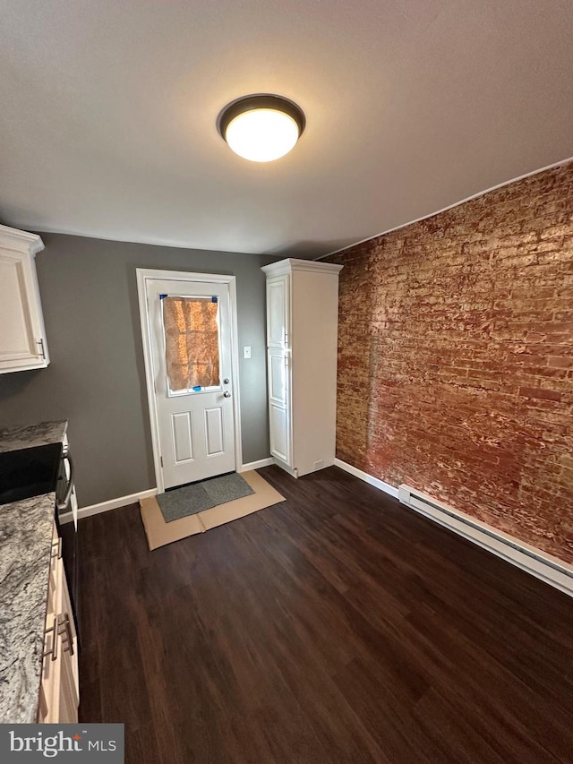 foyer entrance with dark hardwood / wood-style flooring and brick wall