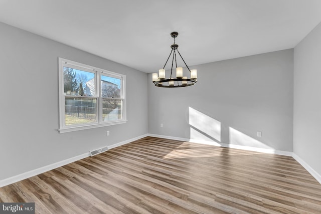 spare room with a chandelier and light hardwood / wood-style flooring