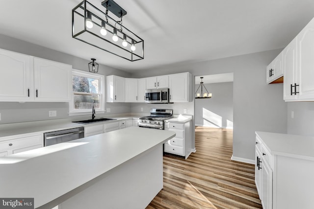 kitchen with pendant lighting, stainless steel appliances, sink, and white cabinets