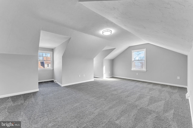 bonus room with dark carpet, a wealth of natural light, and a textured ceiling