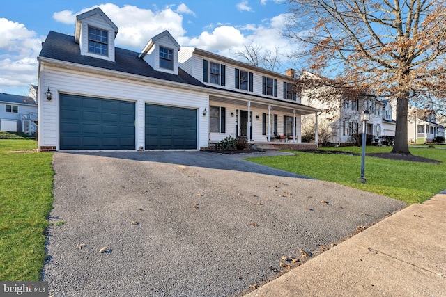 view of front of house featuring a garage, a front yard, and covered porch