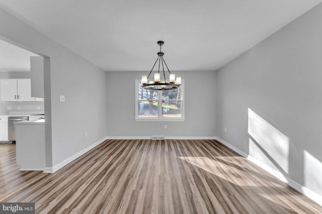 unfurnished dining area with an inviting chandelier and light hardwood / wood-style floors