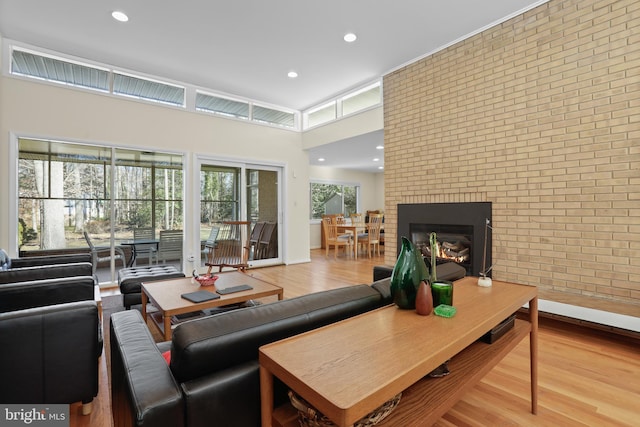 living area with recessed lighting, a fireplace, brick wall, and wood finished floors