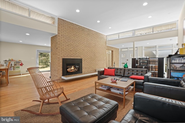 living area featuring brick wall, recessed lighting, a fireplace, and light wood-style floors