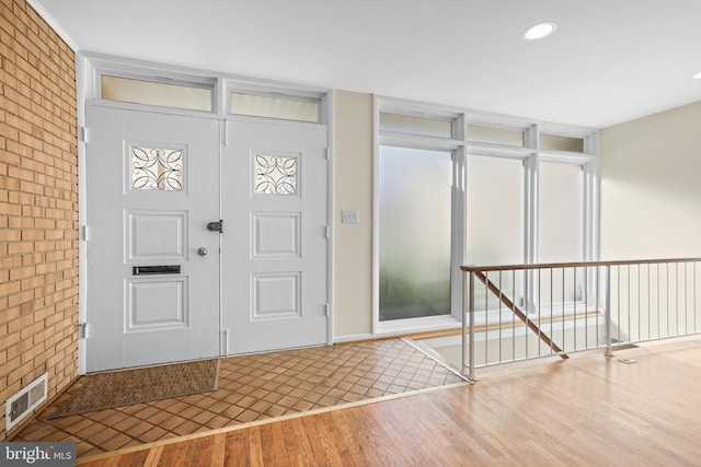 entryway featuring brick wall, visible vents, wood finished floors, and recessed lighting