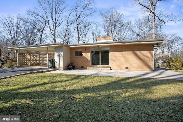 back of house featuring brick siding, a yard, crawl space, a carport, and a chimney