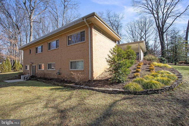 view of side of property featuring brick siding and a lawn