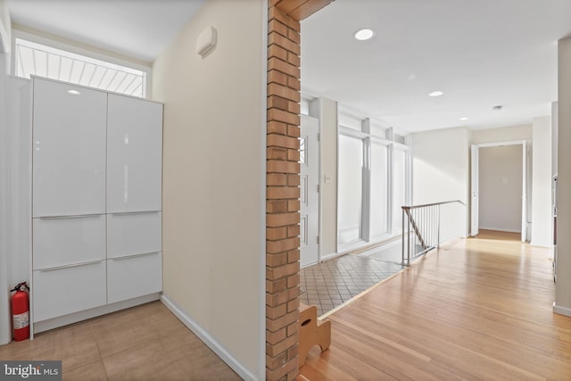 hallway with baseboards, wood finished floors, an upstairs landing, and recessed lighting