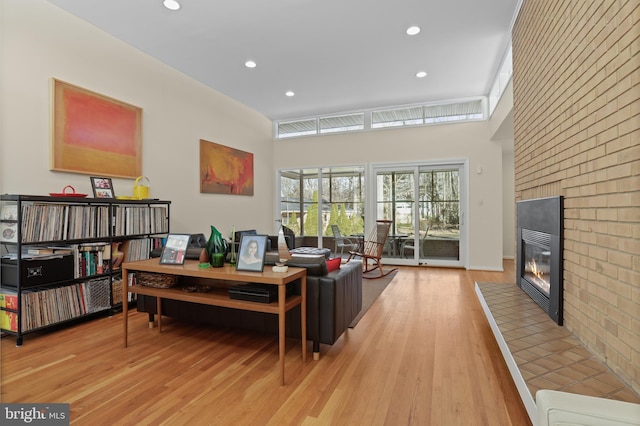 living room featuring a brick fireplace, light wood-style floors, and recessed lighting